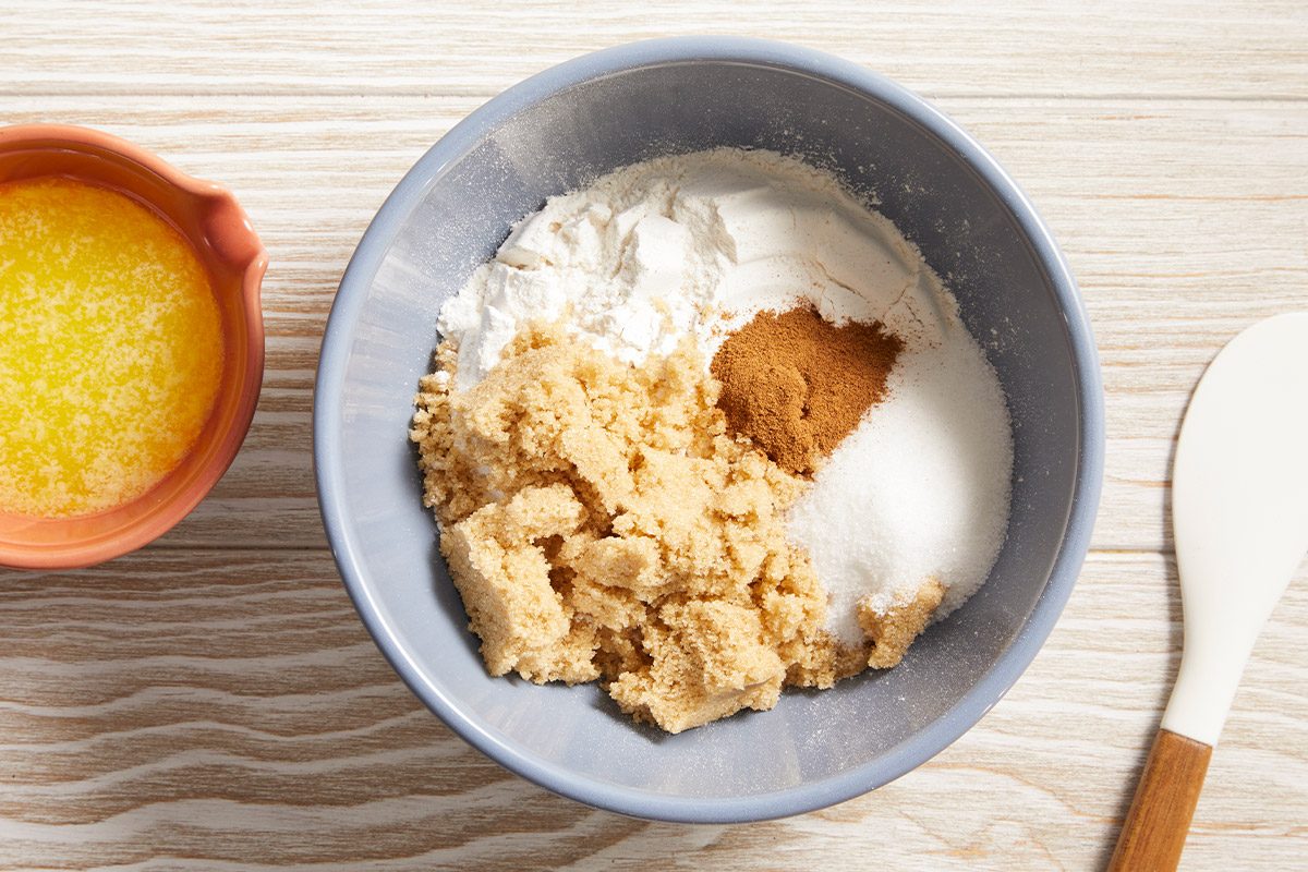 Overhead shot of ingredients in a mixing bowl, flour, brown sugar, cinnamon, and melted butter for the streusel topping.