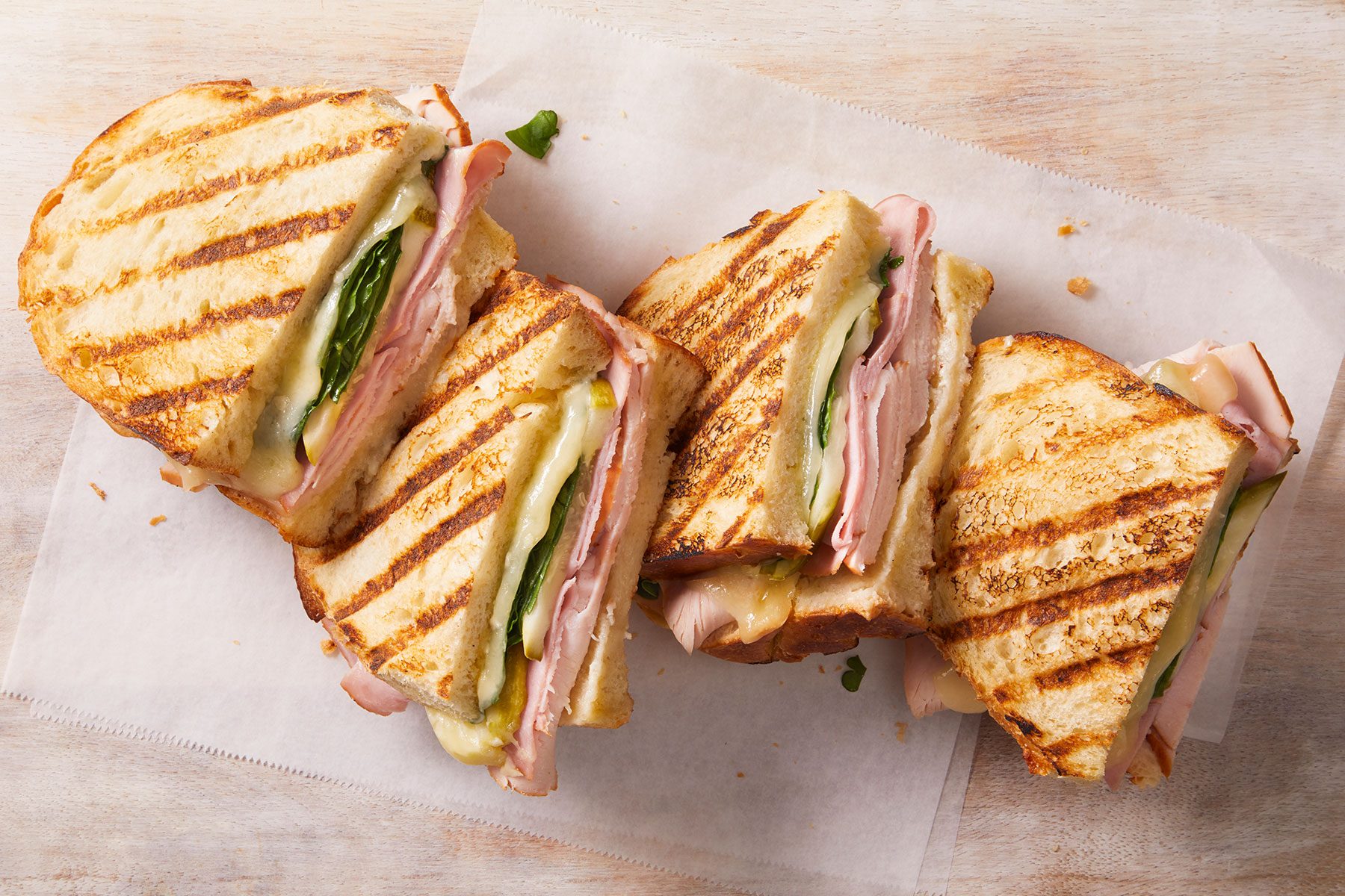 Grilled cuban panini dish of four pieces on a counter.