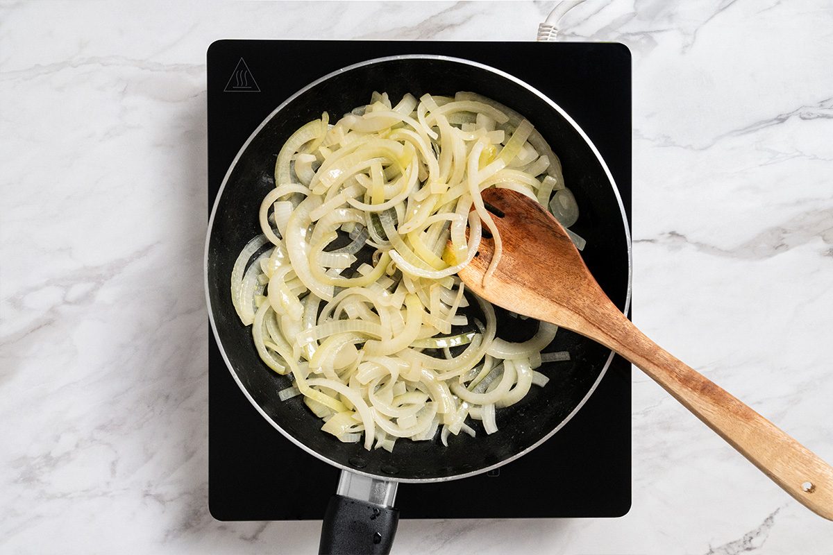 Overhead shot of the same skillet; saute onions in butter until tender; induction; all set on a white marble surface;