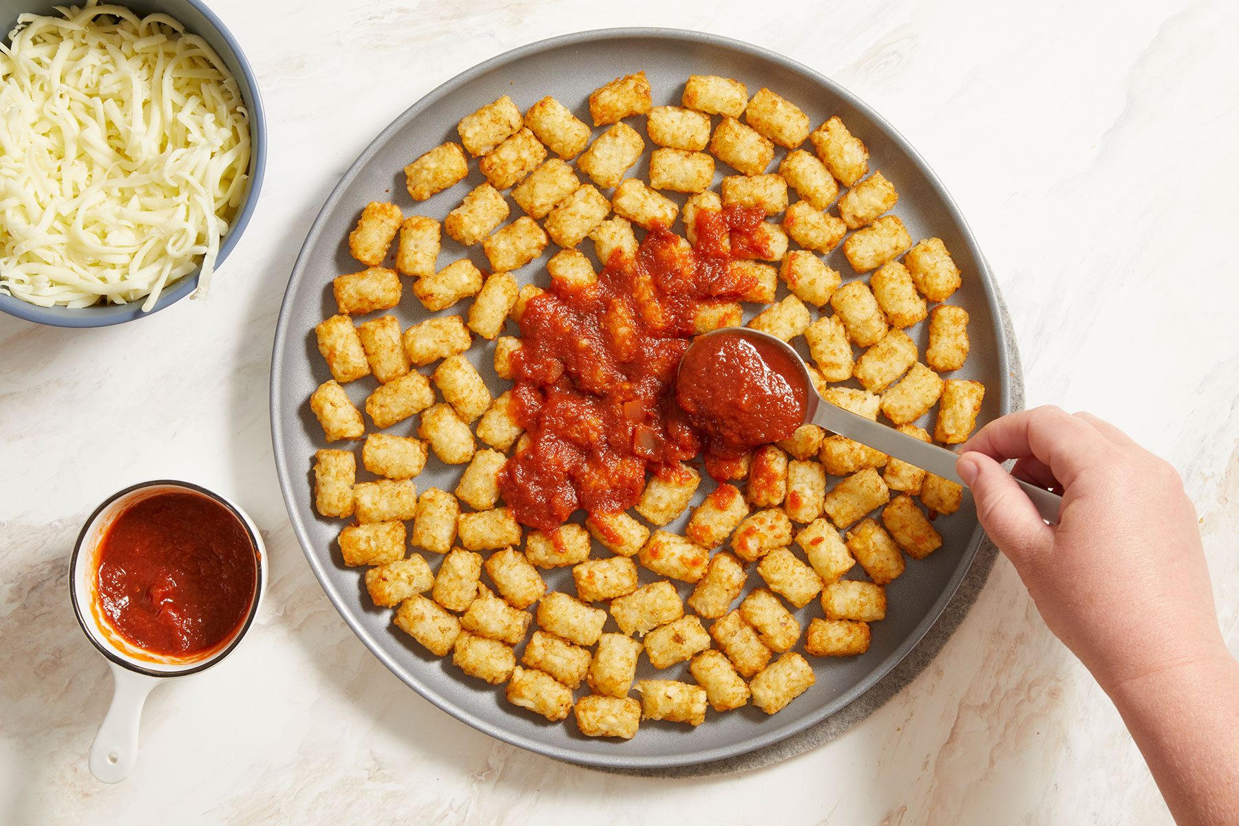 Top the tater tots with pizza sauce, cheese and pepperoni in a pan.
