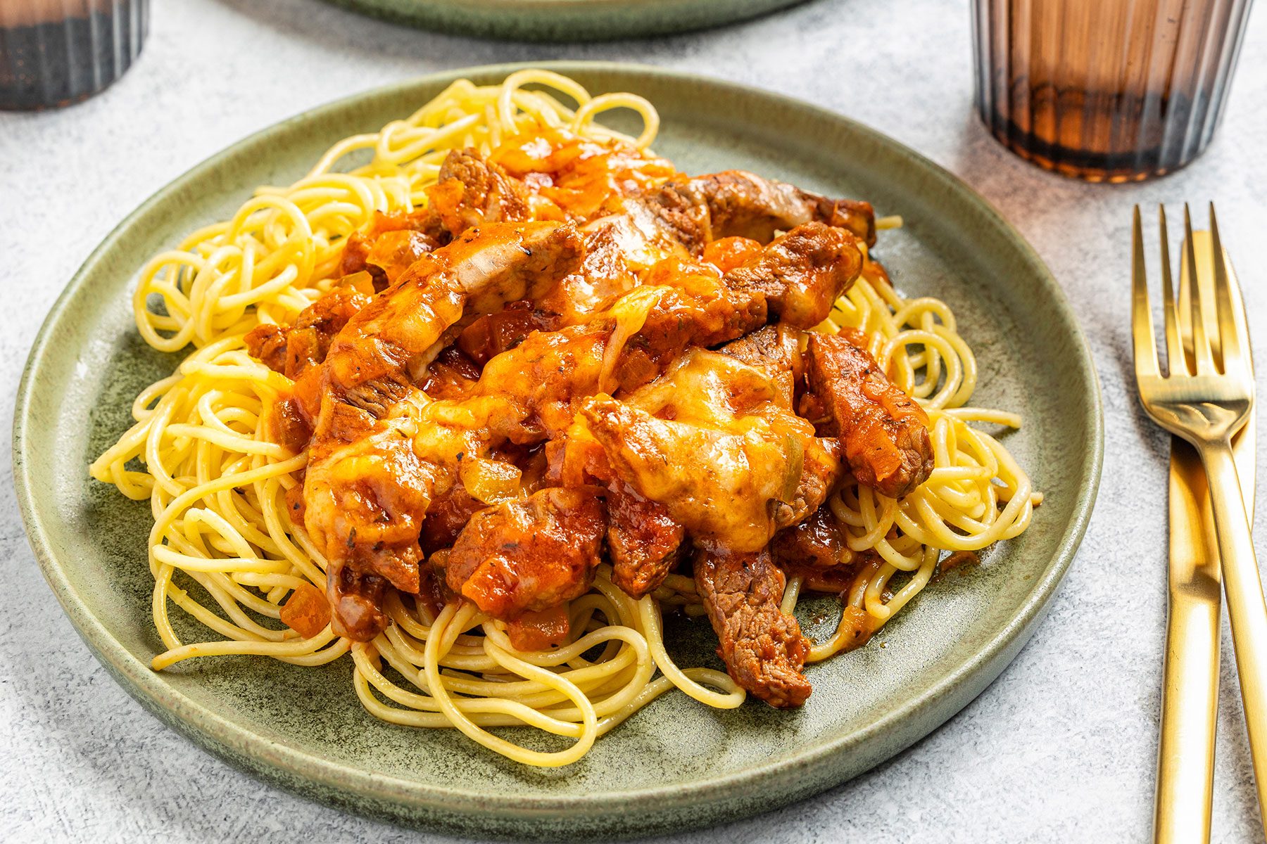 Steak And Spaghetti on a plate with a fork kept on side.