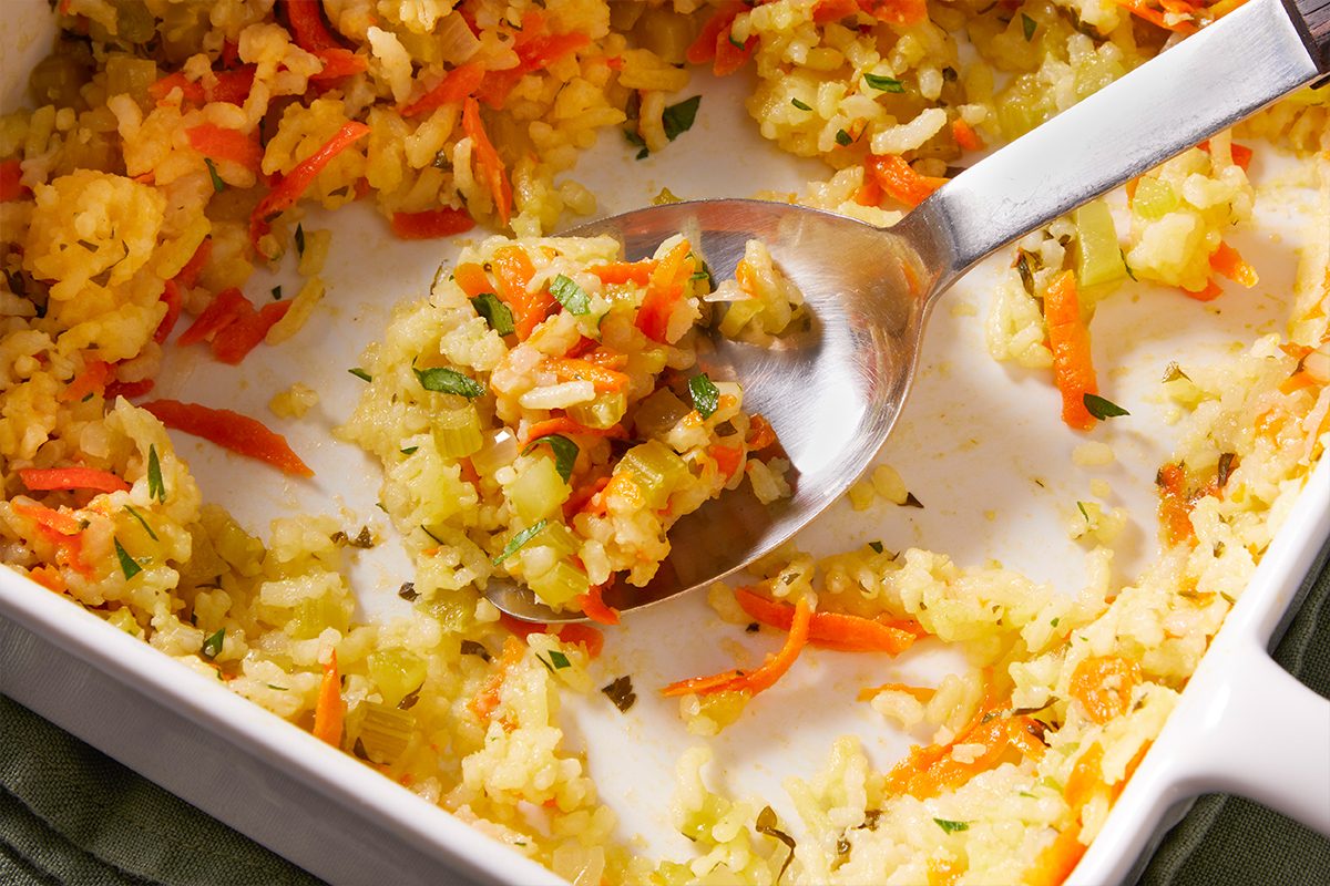 Close-up of Baked Rice Pilaf in a baking dish with a spoon resting inside.