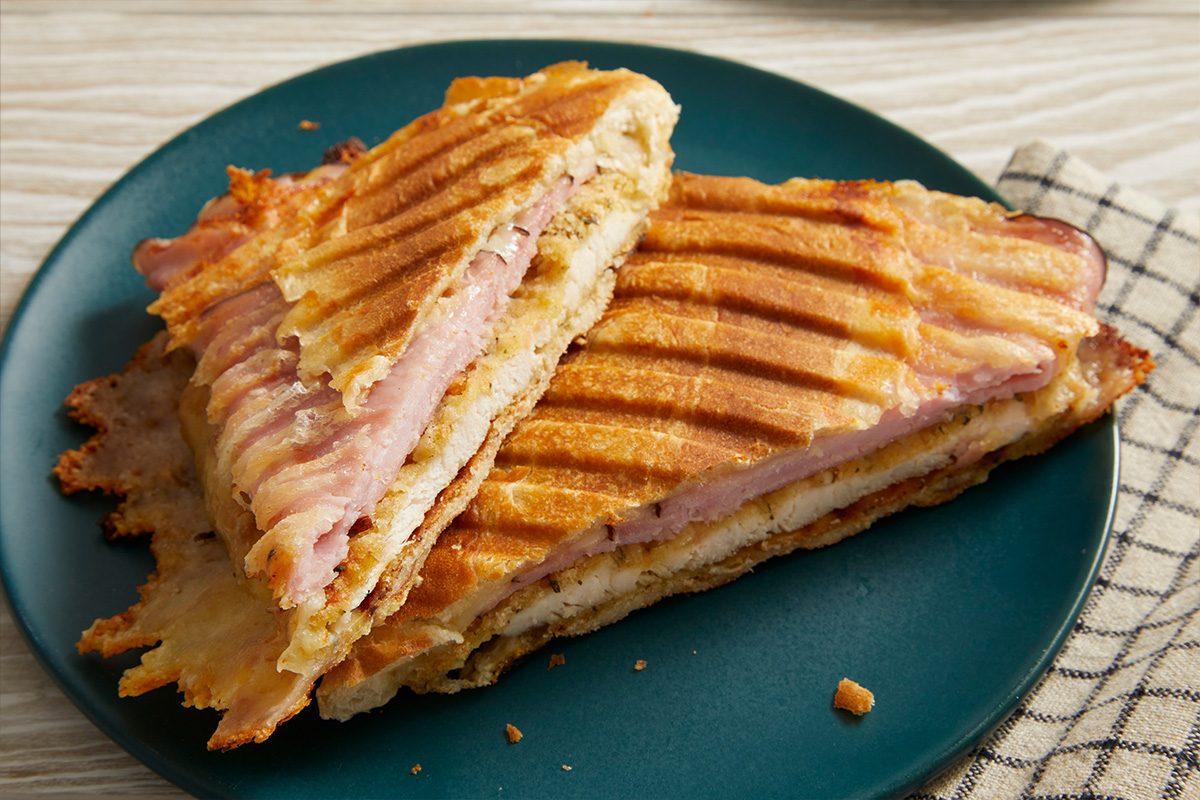 Close-up overhead shot of a toasted Chicken Cordon Bleu Sandwich with melted cheese and ham layers visible.