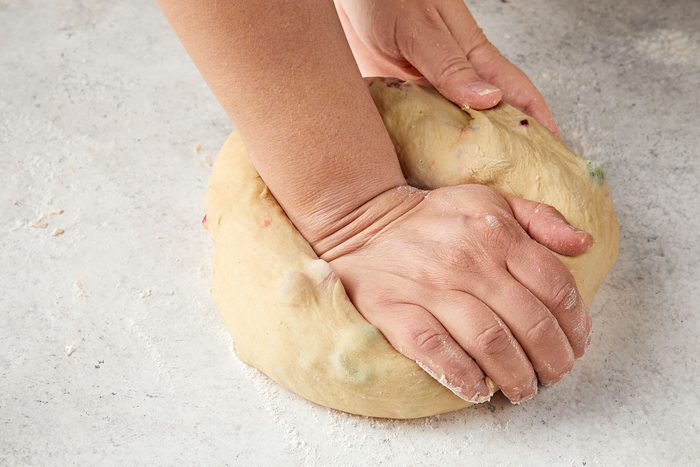 Punching the dough down using your knuckles expelling some of the air from the dough.