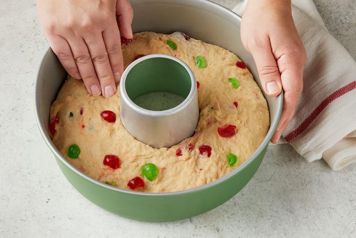 Patting dough evenly into a greased 10-inch tube pan with kitchen towel placed on side.
