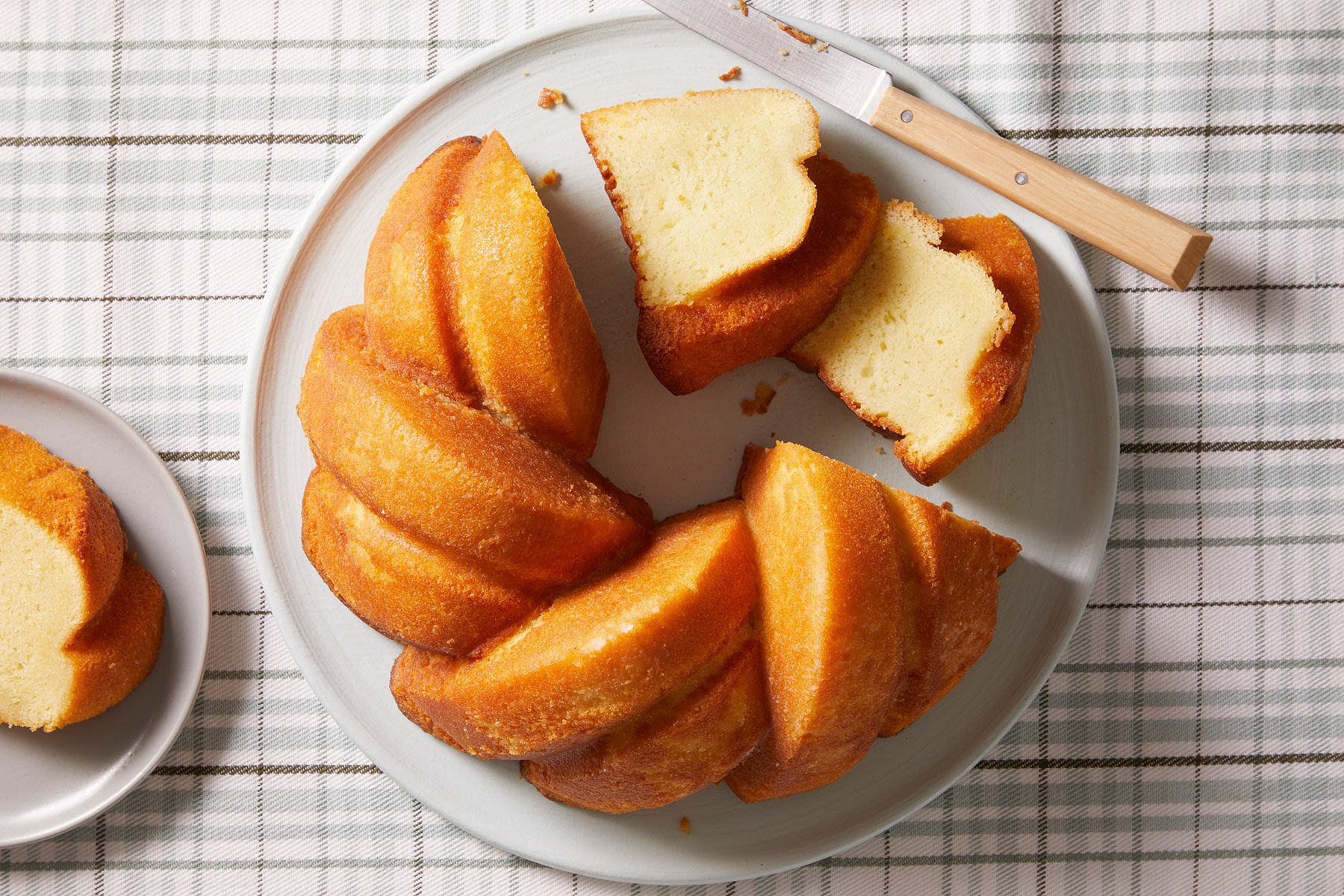 Coconut Rum Cake with small pieces cut with a knife placed on side on the plate.