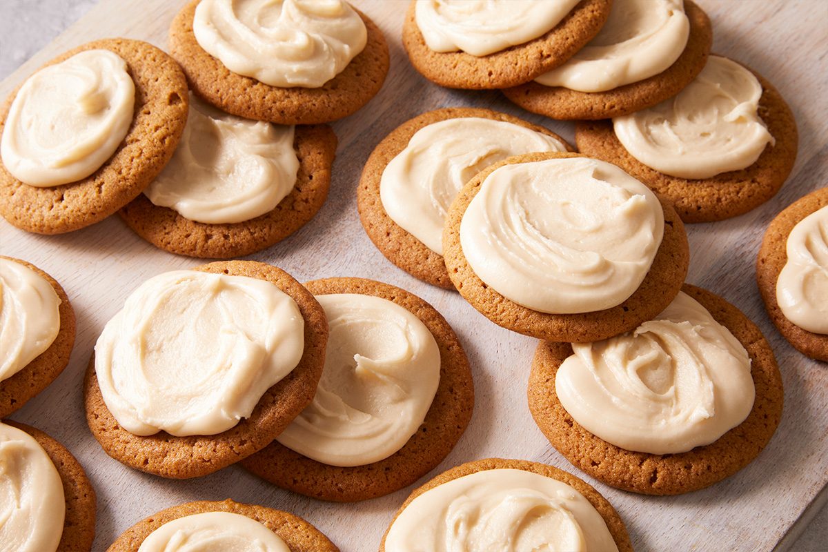 Overhead shot of Frosted Ginger Cookies arranged neatly on parchment paper with thick, creamy icing swirls