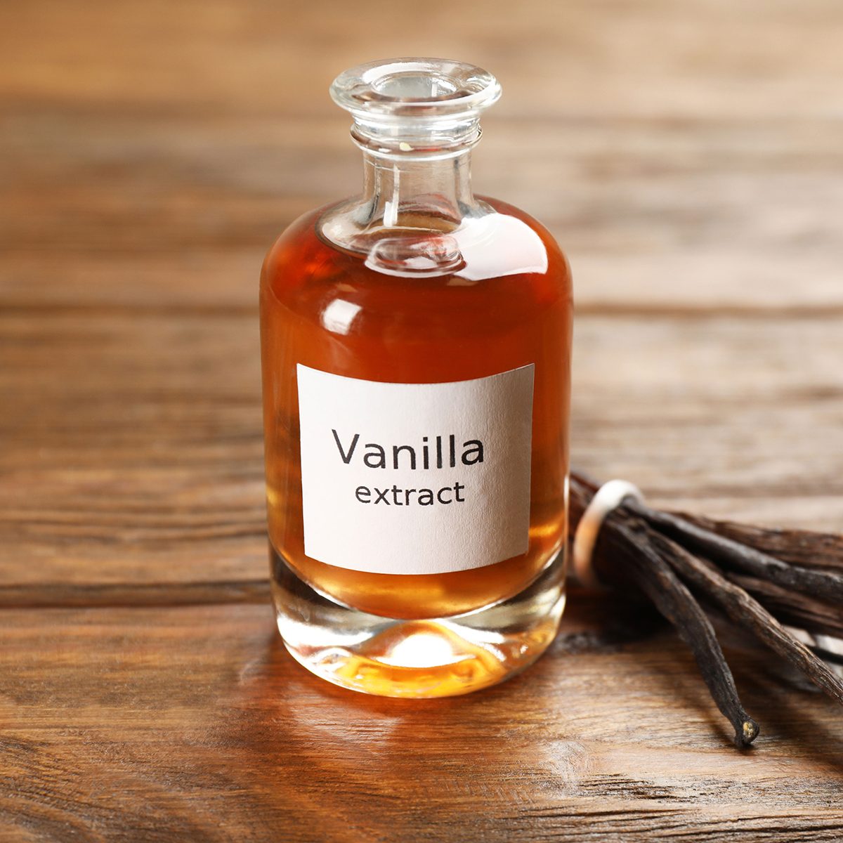 Aromatic vanilla extract and beans on wooden table