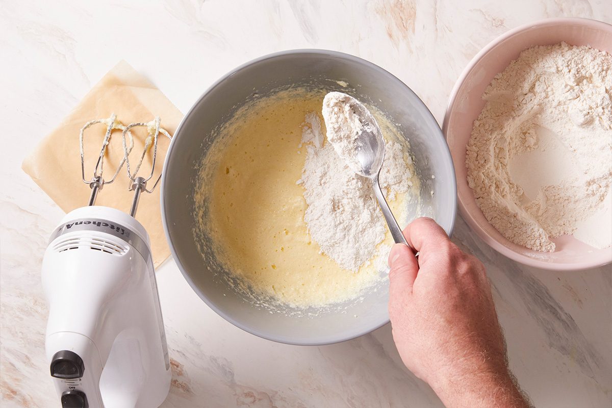 Overhead shot of a stand mixer bowl filled with smooth biscotti batter and a bowl of flour beside it.