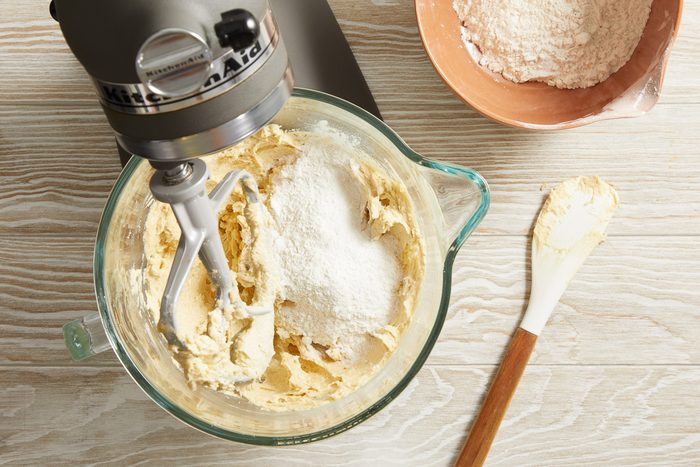 flour, baking soda and salt mixture being added to butter, vanilla and eggs mixture