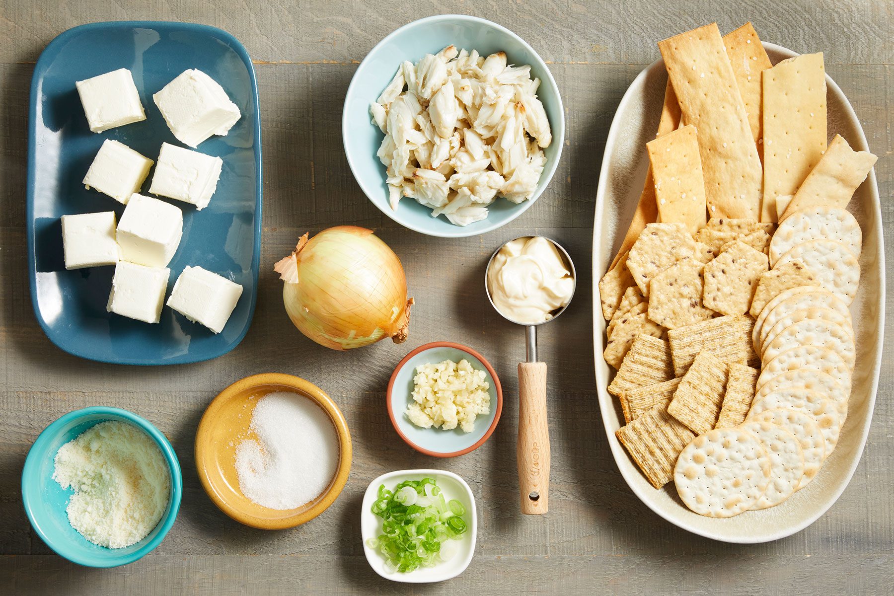 Ingredients for Slow-Cooker Crab Dip in small bowls and plates on kitchen counter.