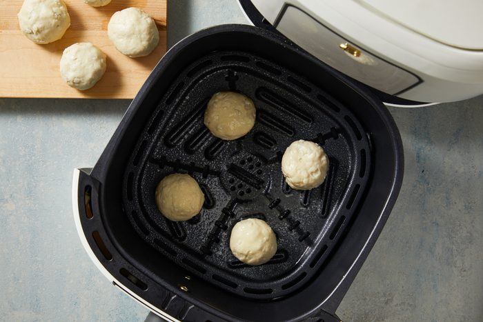doughnuts placed in a single layer onto a greased air-fryer basket