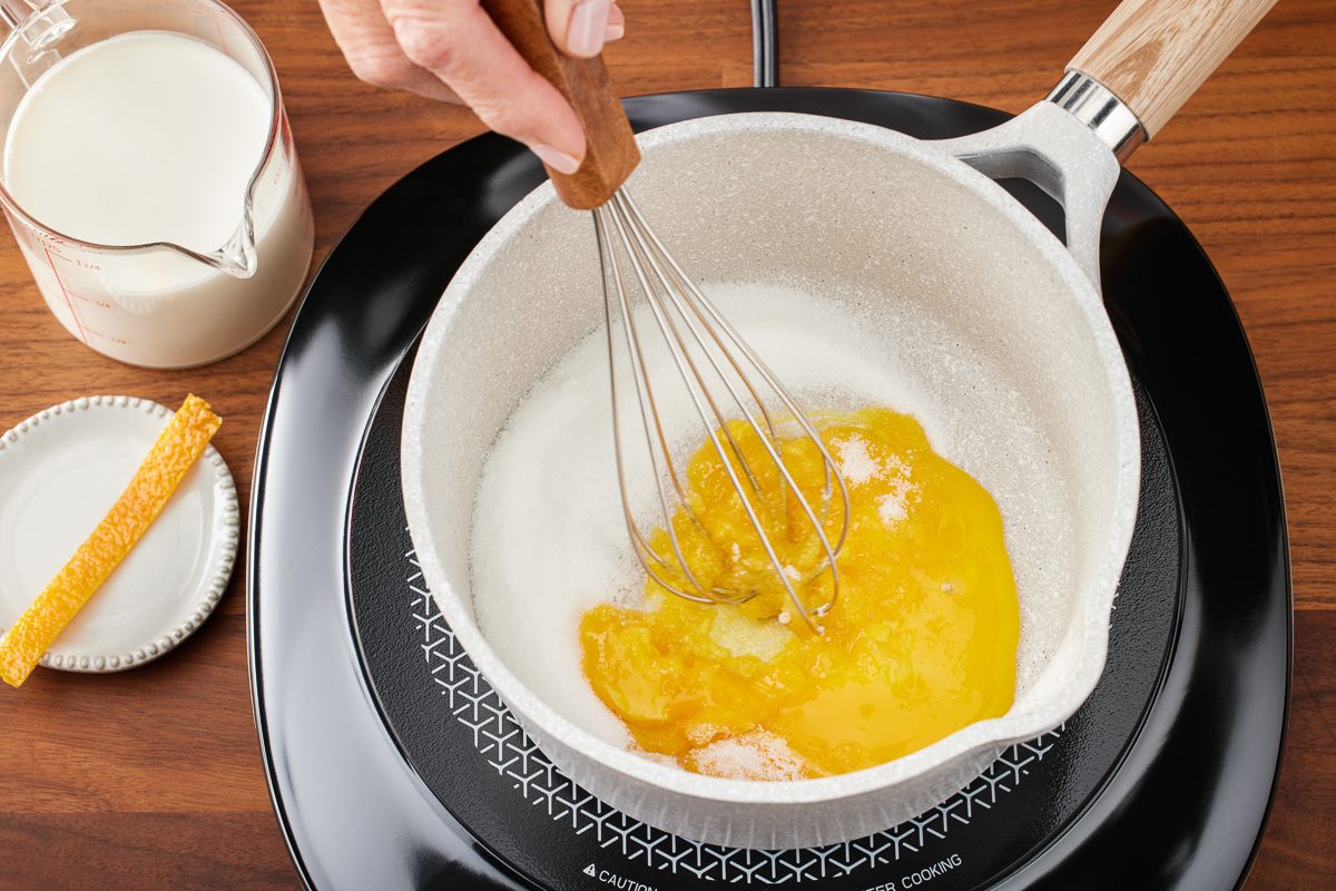 egg yolks and sugar being whisked together in a saucepan