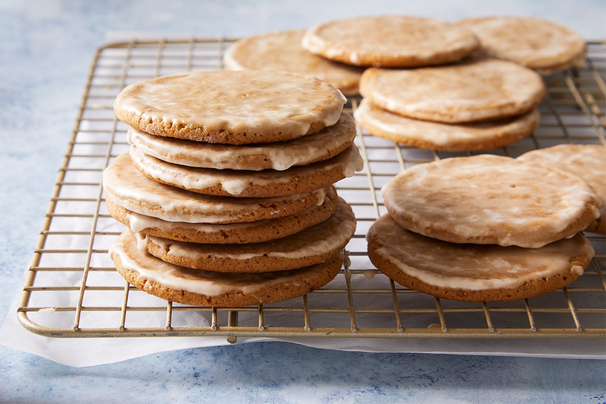 Horizontal shot of glazed Gingerbread Latte Cookies sits on a metal cooling rack lined with parchment paper the light blue surface adds contrast